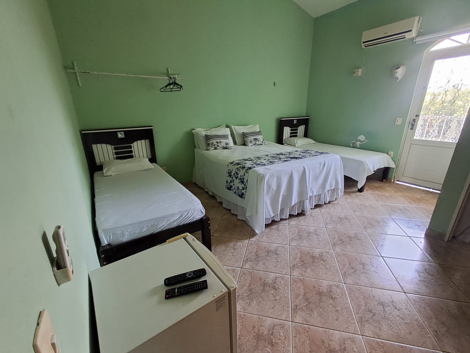 Quarto verde com uma cama de casal e duas camas de solteiro
